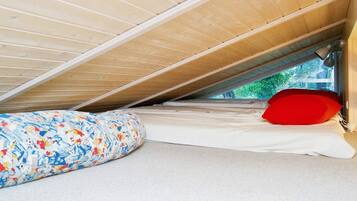 A small, enclosed sleeping area with a sloped ceiling, a mattress, and a pillow.