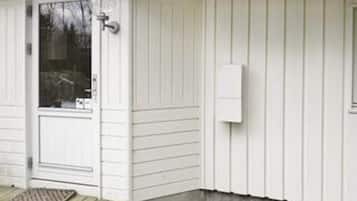 A white exterior wall with a door, a window, and a wall-mounted electrical box.