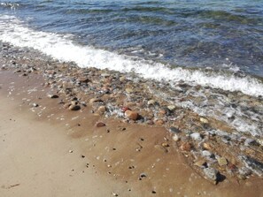 Ein Strand mit klarem Wasser, Kieselsteinen und Sand.