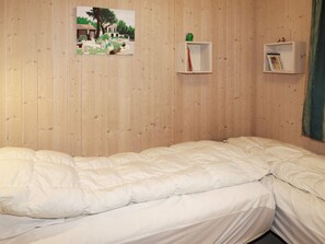 A room with a bed, a picture on the wall, and two small shelves.