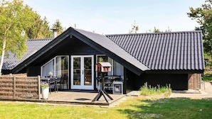 A modern house with a sloped roof, large glass doors, and a covered patio area. - 6 Person Holiday Home in Saltum (Saltum)