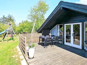 Um terraço com mesa e cadeiras, um parquinho e uma área de varanda coberta.
