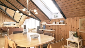 A cozy, wooden-furnished dining area with a round table, chairs, and a ceiling skylight. - 6 Person Holiday Home in Saltum (Saltum)