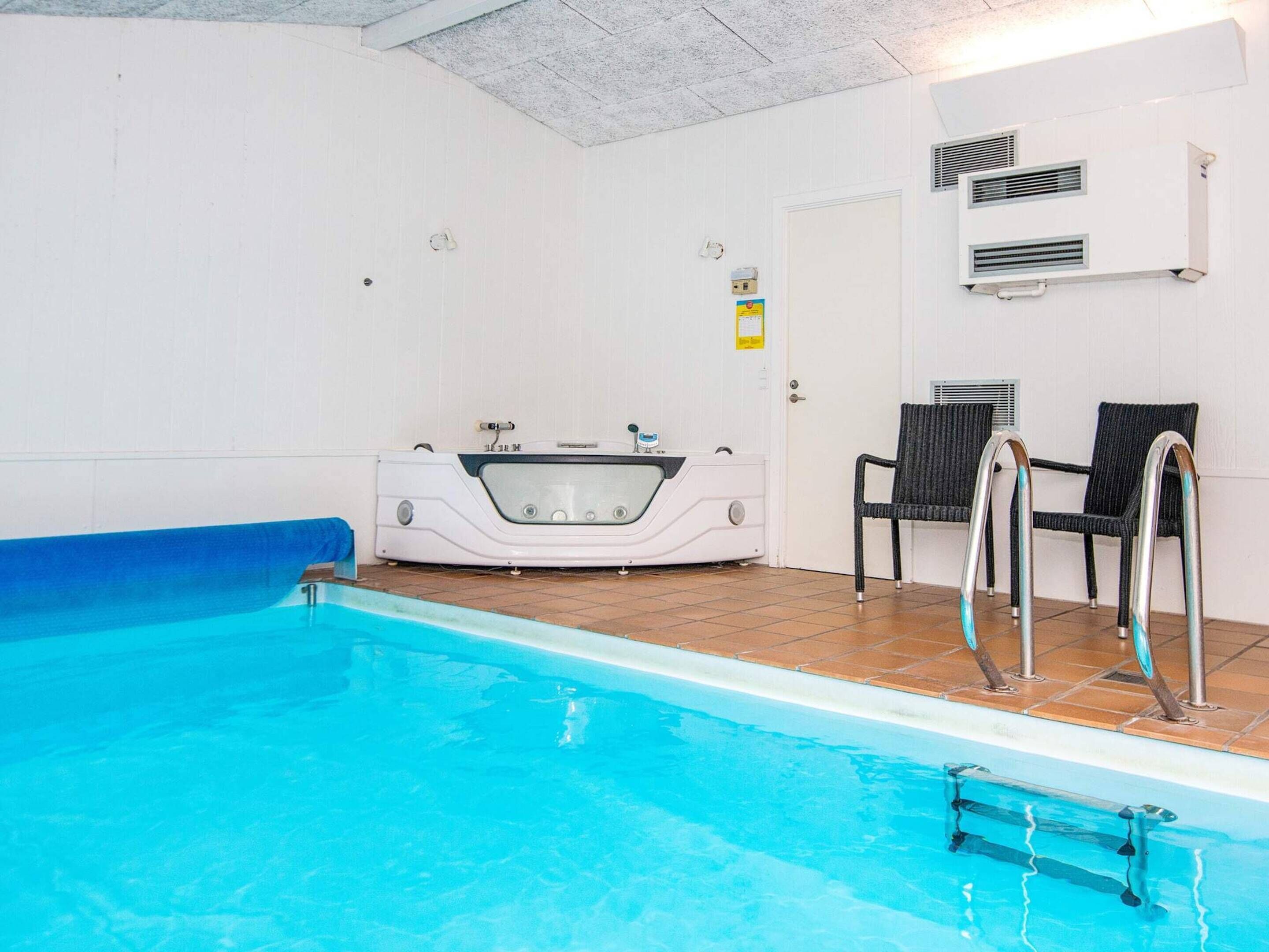 A swimming pool with a jacuzzi, two chairs, and a door.