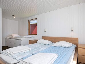 A bedroom with two beds, a small bedside table, a nightstand, a window, and a wall-mounted light fixture. - 8 Person Holiday Home in Hjorring (Hjørring)