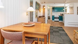 Een gezellige keuken met blauwgroene kastjes, een houten eettafel en een vloerkleed met een patroon.