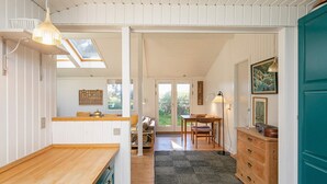 Een gezellig interieur met een houten toonbank, een eethoek en een groene deur.
