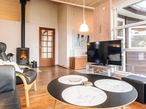 Una sala de estar acogedora con chimenea, sofá de cuero, televisor de pantalla plana y mesa de comedor con cubierta de mármol.