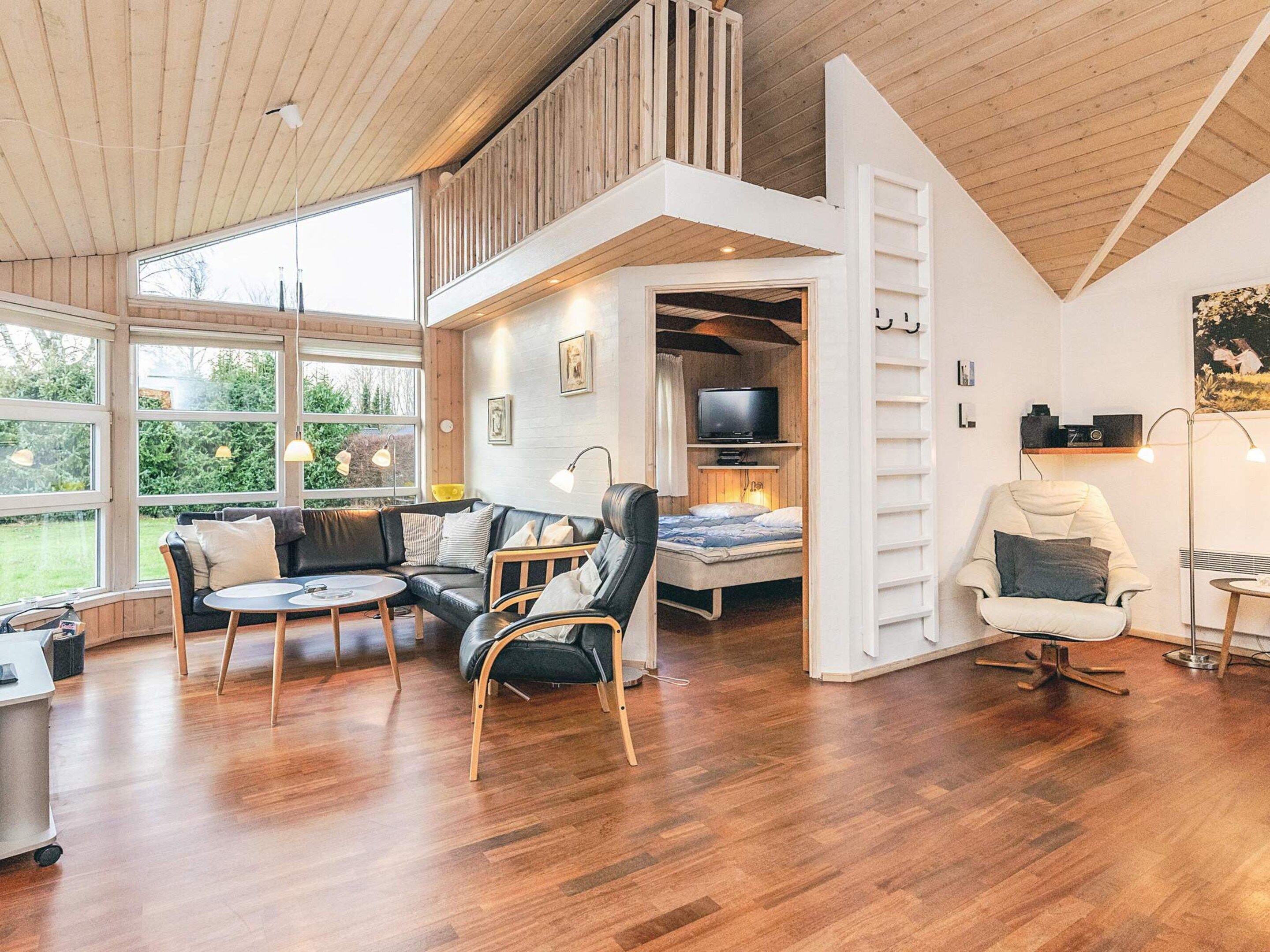Ein geräumiges Loft mit einer Schlafhöhle, einer Sitzecke inklusive Sofa und Sesseln, einem Fernseher und einem Esstisch.