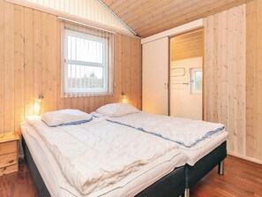 A bedroom with a bed, wooden walls, a window, and a door. - 5 Star Holiday Home in Hals (Hals)