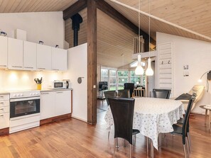 A modern kitchen with white cabinets, a microwave, and a stove. There is a dining area with a table and chairs.