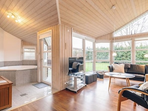 A modern interior with a wooden ceiling, a bathtub, a sofa, and a dining area.