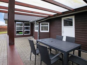 A covered patio area with a table and chairs, a window, and a door.