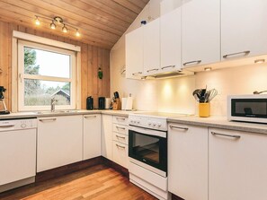 A modern kitchen with white cabinets, a Bosch dishwasher, a stove, and a microwave. - 5 Star Holiday Home in Hals (Hals)