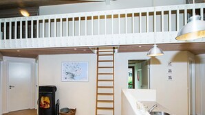 Una cocina moderna con estufa integrada, una escalera de madera y una lámpara colgante.