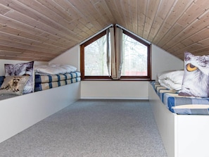 A loft bedroom with a sloped ceiling, a large window, and a view of trees. - 4 Star Holiday Home in Aabenraa (Aabenraa)