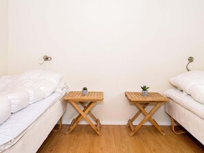 A bedroom with two single beds, wooden nightstands with small plants, and a plain wall. - 4 Star Holiday Home in Aabenraa (Aabenraa)