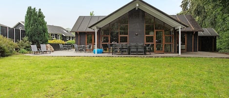 A building with a large patio area, outdoor seating, and a grassy lawn.