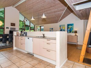 A modern kitchen with a central island, pendant lighting, and a view of the outdoors. - 4 Star Holiday Home in Aabenraa (Aabenraa)