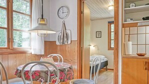 A cozy room with a wooden floor, a dining table with chairs, a bed, and a kitchen area with a sink and cabinets. - 6 Person Holiday Home in Ronne (Ronne)