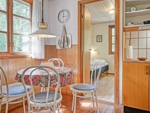 A cozy room with a wooden floor, a dining table with chairs, a bed, and a kitchen area with a sink and cabinets. - 6 Person Holiday Home in Ronne (Ronne)