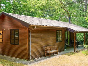 A wooden cabin with a porch, a bench, and a covered seating area. - 6 Person Holiday Home in Ronne (Ronne)