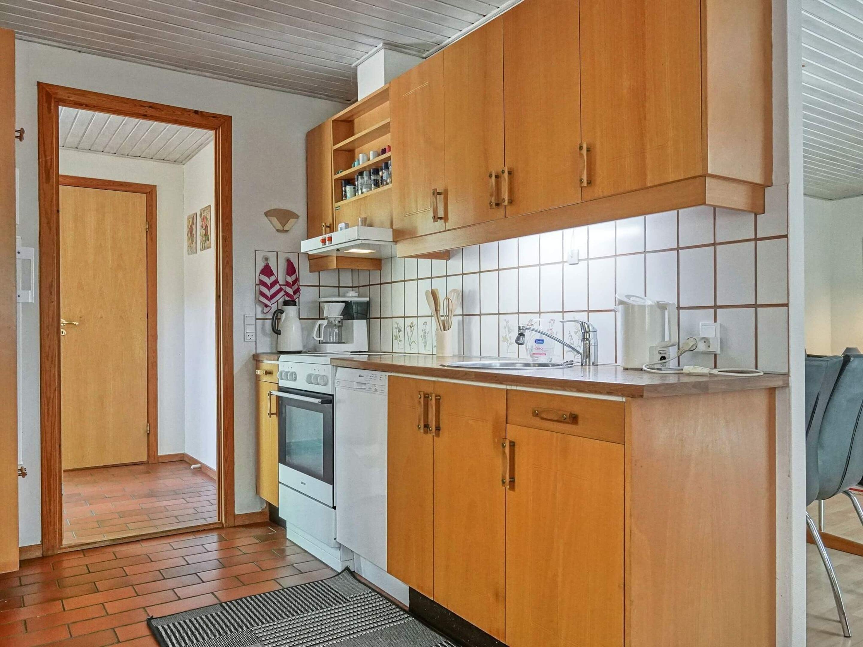 Une cuisine avec des meubles de rangement en bois, une cuisinière, un lave-vaisselle et un évier.
