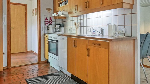 A kitchen with wooden cabinets, a stove, a dishwasher, and a sink. - 6 Person Holiday Home in Ronne (Ronne)
