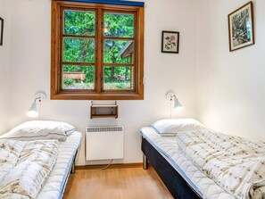 A bedroom with two beds, a window with a view of greenery, a wall-mounted heater, and a small shelf. - 6 Person Holiday Home in Ronne (Ronne)