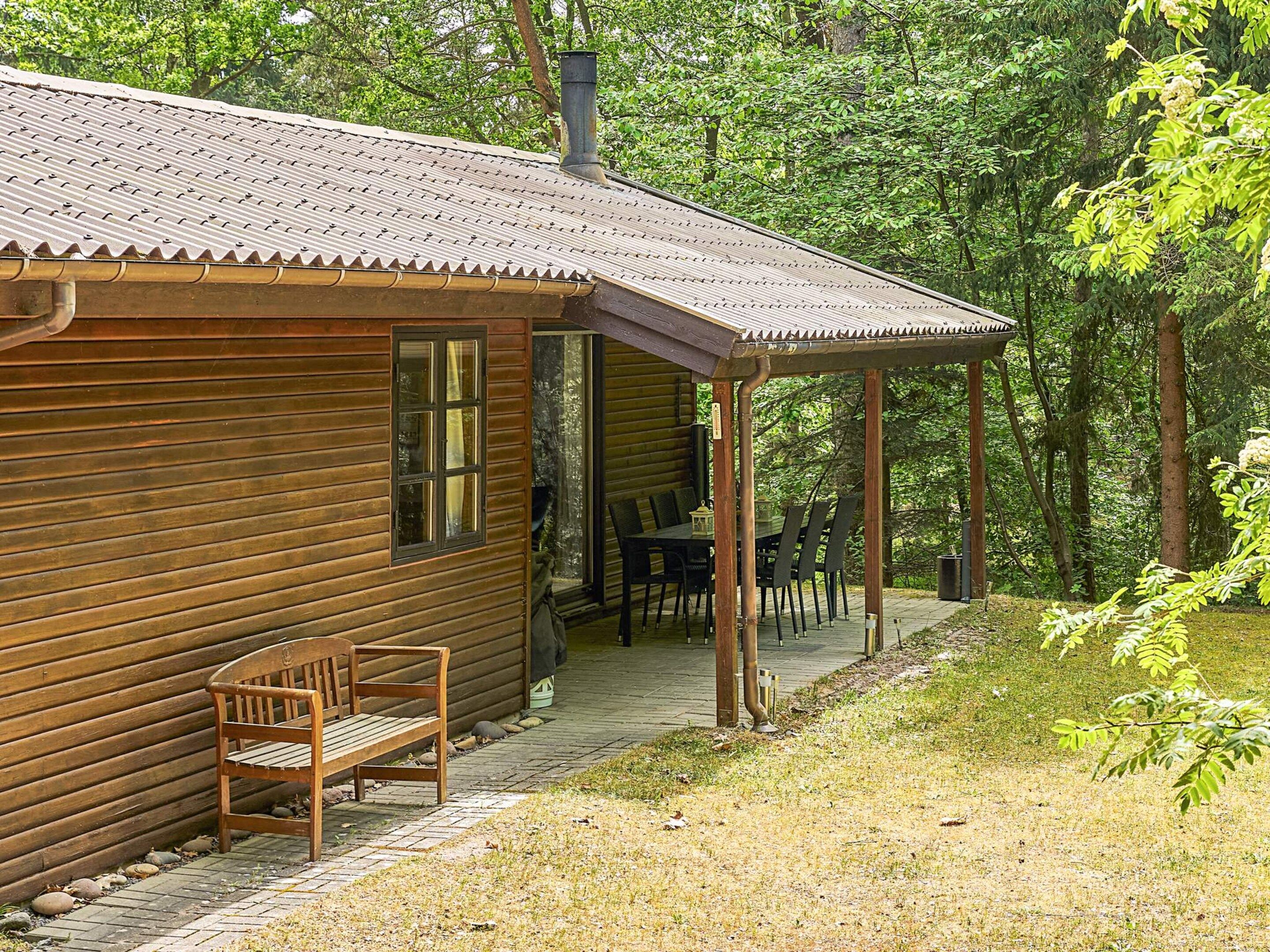 A wooden cabin with a porch, a table, and chairs.