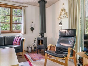 A cozy living room with a fireplace, a sofa, a chair, and a television. - 6 Person Holiday Home in Ronne (Ronne)