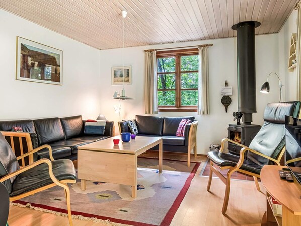 Ein gemütliches Wohnzimmer mit einer Couch, Sesseln, einem Couchtisch und einem Kamin.