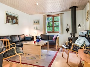 Uma sala de estar aconchegante com sofá, poltronas, mesa de centro e lareira.