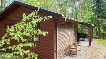 A wooden cabin with a covered porch and a dining table.