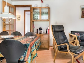 Uma sala de jantar com uma mesa posta para quatro pessoas, um armário com portas de vidro e duas cadeiras de couro.
