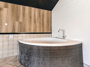 A modern bathroom with a freestanding bathtub, a wooden accent wall, and a tiled floor.
