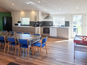 A modern kitchen with a dining area, a pool table, and a view of the outdoors.