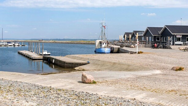 Una marina costera con barcos amarrados, un muelle y un edificio con terraza.