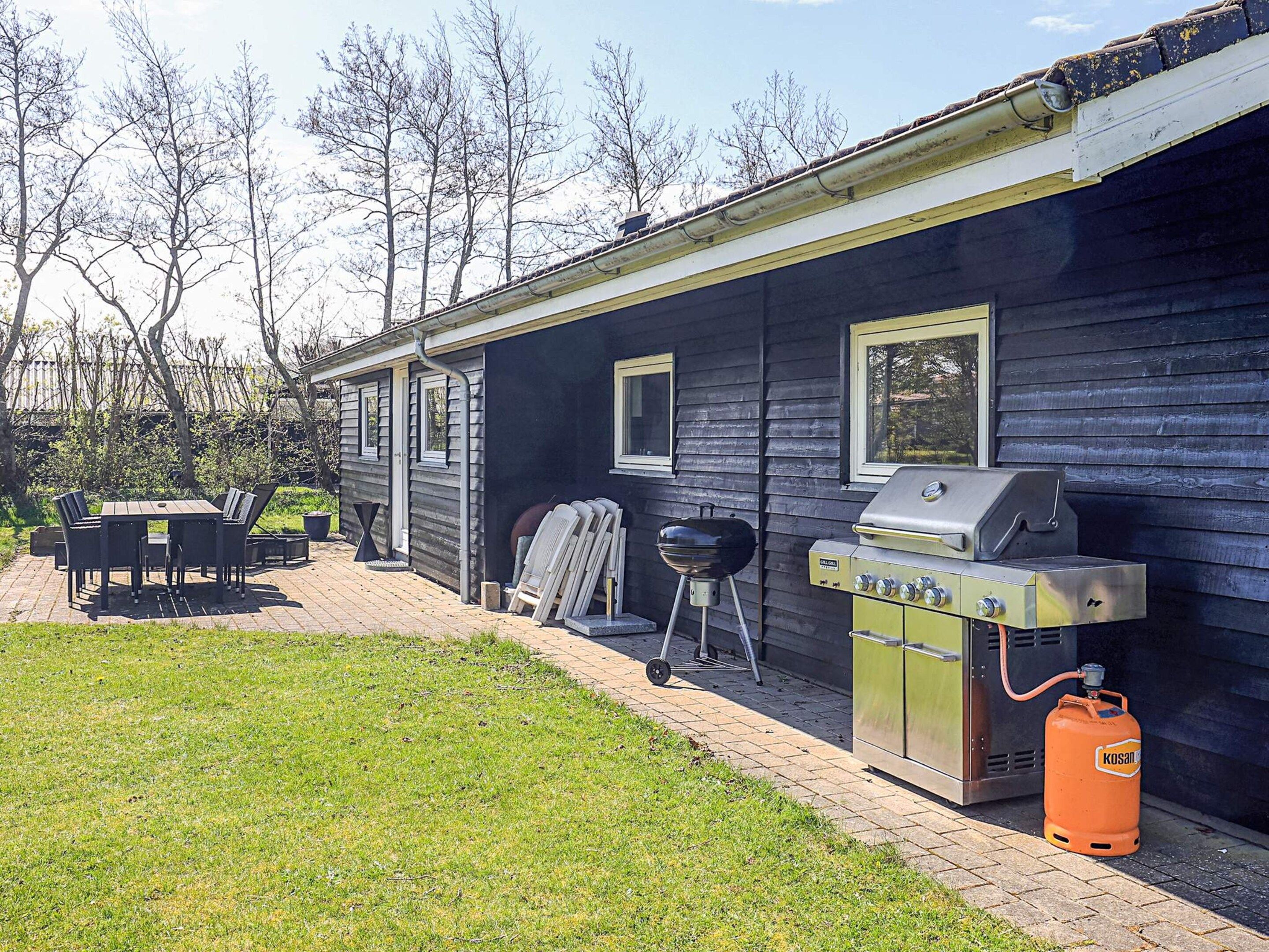 Ein Haus mit Grill und Gasflasche vor der Fassade.