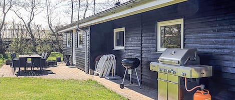 A house with a barbecue grill and a gas tank outside.