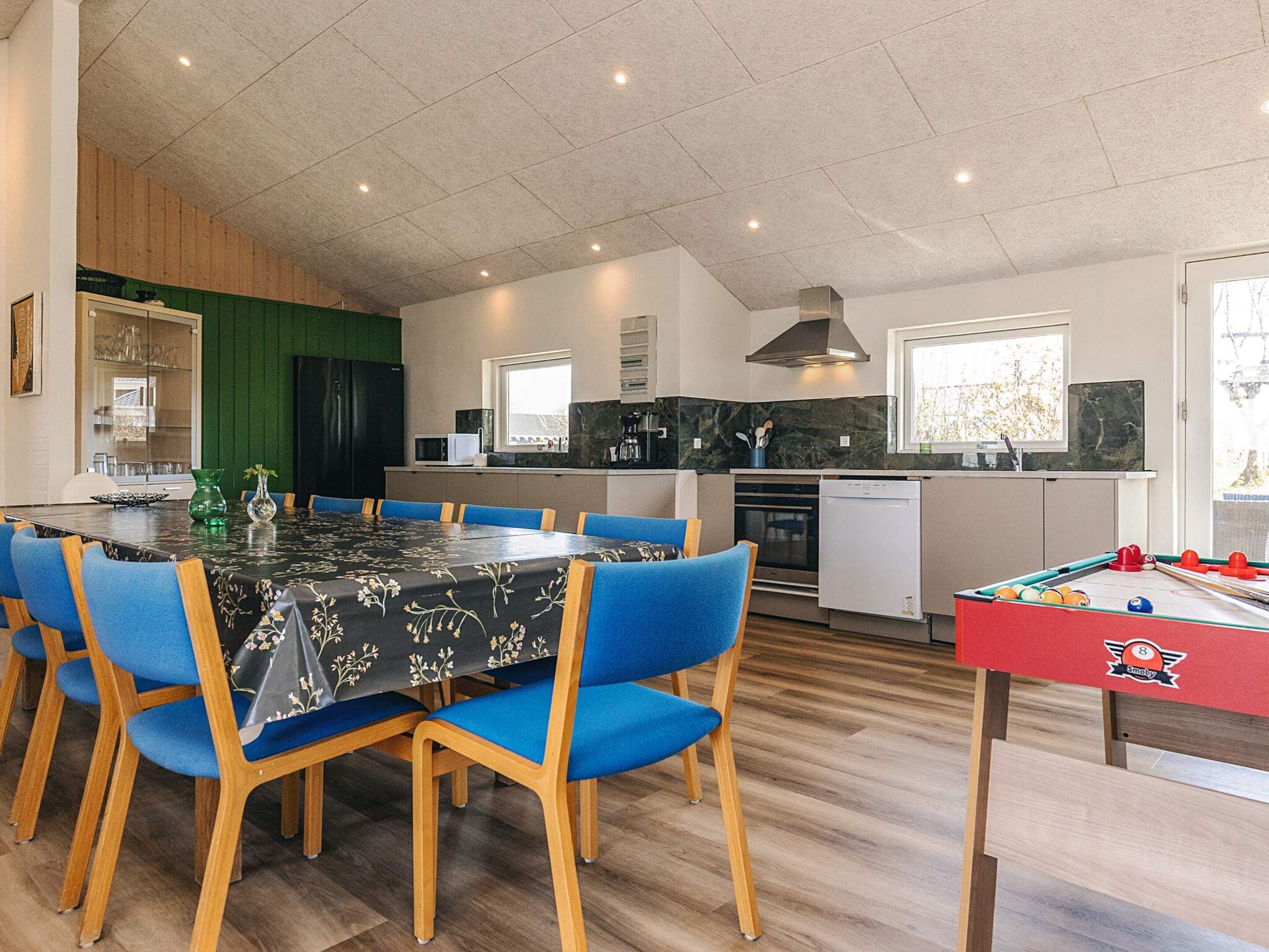 A dining area with a table and chairs, a kitchen with appliances, and a pool table.