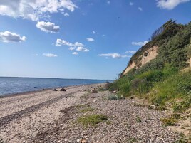 Una playa de guijarros con cielo despejado y agua distante.