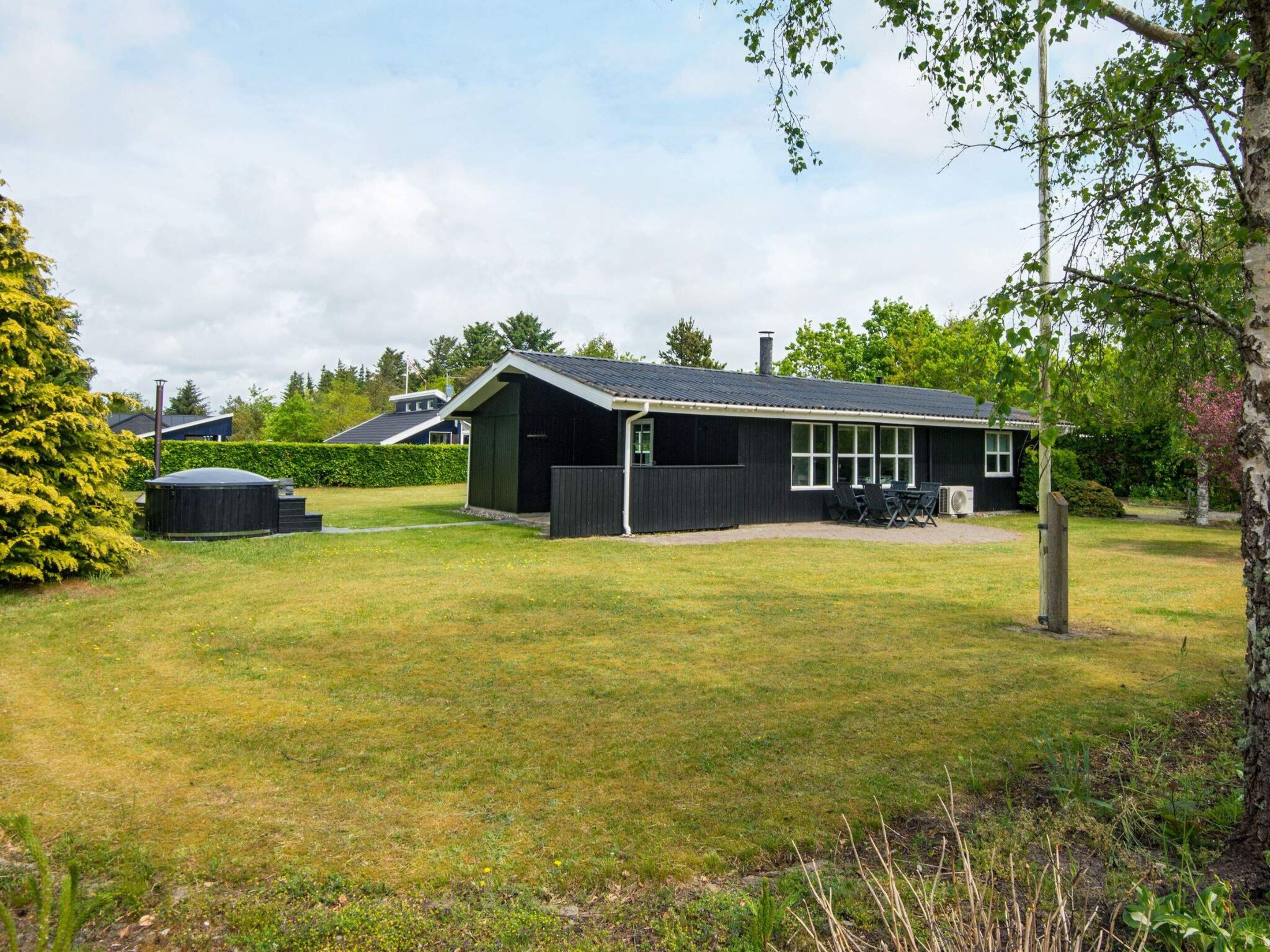 A black house with a covered patio and a lawn.