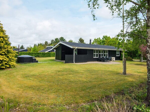 A black house with a covered patio and a lawn.