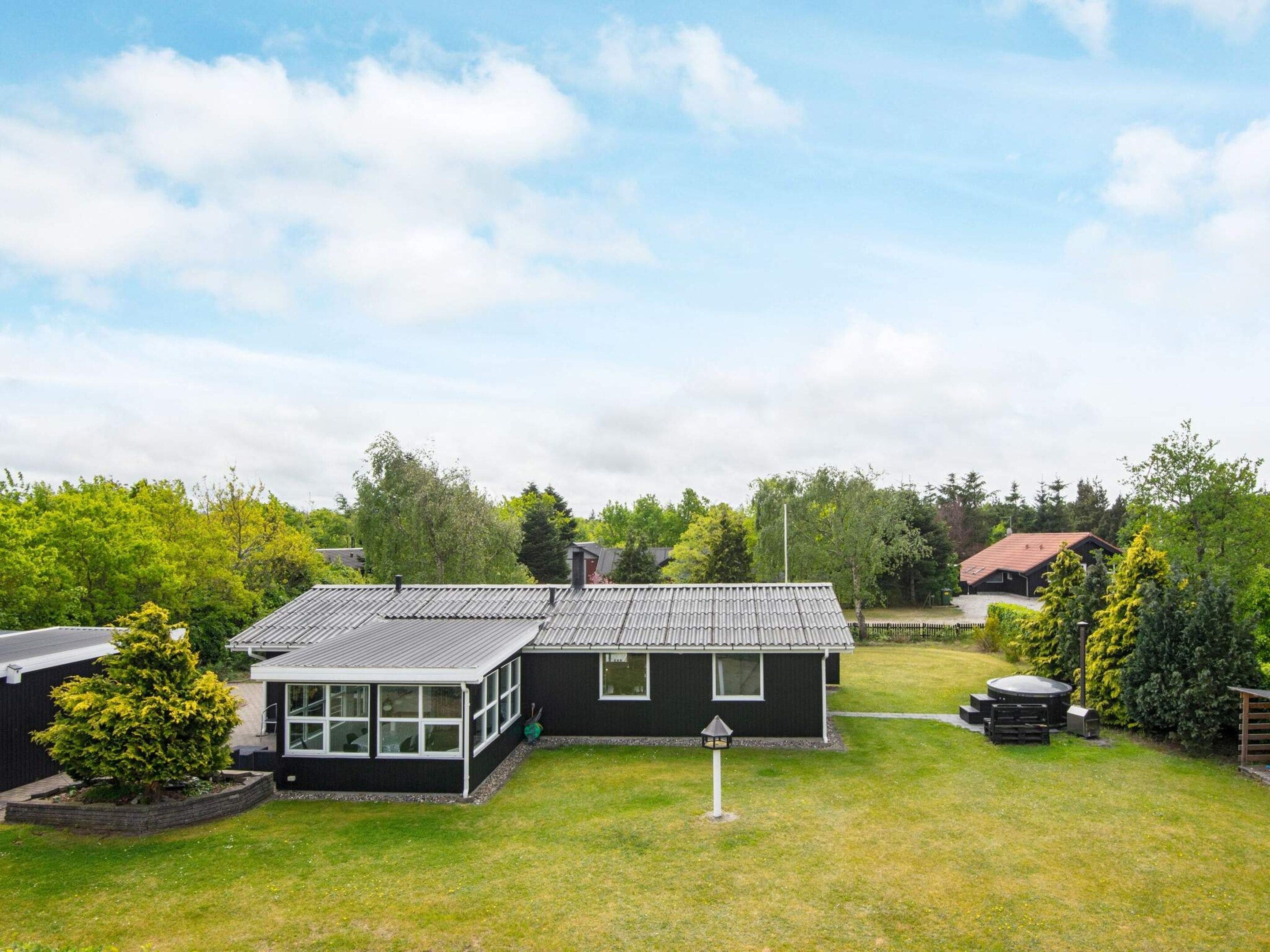 Une maison moderne à deux étages, dotée d’une grande cour avant, d’un porche abrité et d’un petit jardin.