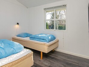 Ein Schlafzimmer mit zwei Betten, einem Fenster und einer Wandleuchte.