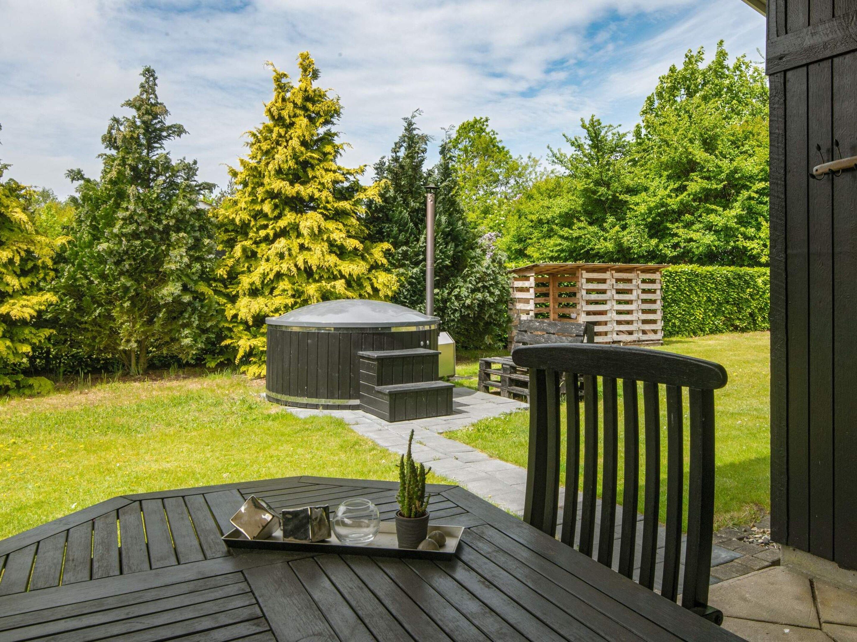 A patio with a table, a hot tub, and a wooden deck.
