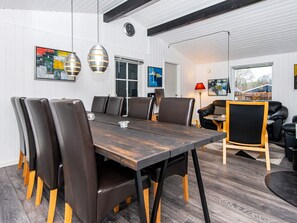 A modern dining area with a long table, multiple chairs, pendant lights, and artwork on the walls. - 7 Person Holiday Home in Ulfborg (Ulfborg)