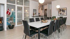 Ett modernt matområde med ett vitt bord och svarta stolar, stora fönster och ett kök i bakgrunden.