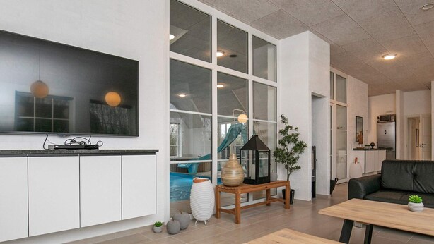 Ett modernt vardagsrum med en stor TV, ett soffbord i trä och en svart soffa.